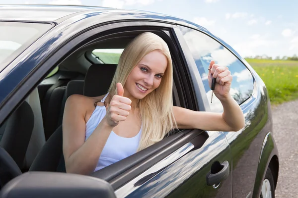 Mulher feliz em um carro mostrando uma chave — Fotografia de Stock