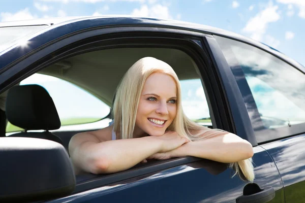 Junge blonde Frau lehnt an Autoscheibe — Stockfoto