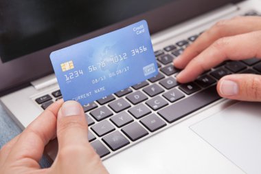 Dizüstü bilgisayarlı ve kredi kartlı adam online alışveriş yapıyor.