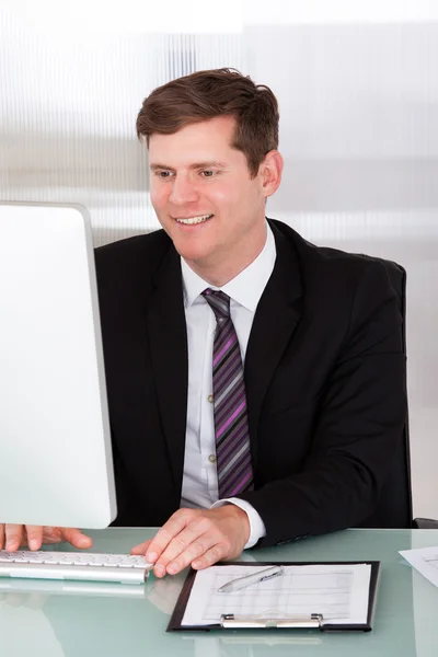 Glücklicher junger Mann, der im Büro arbeitet — Stockfoto