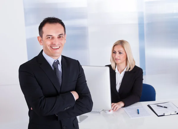 Бизнесмен, стоящий перед своим коллегой с помощью компьютера — стоковое фото