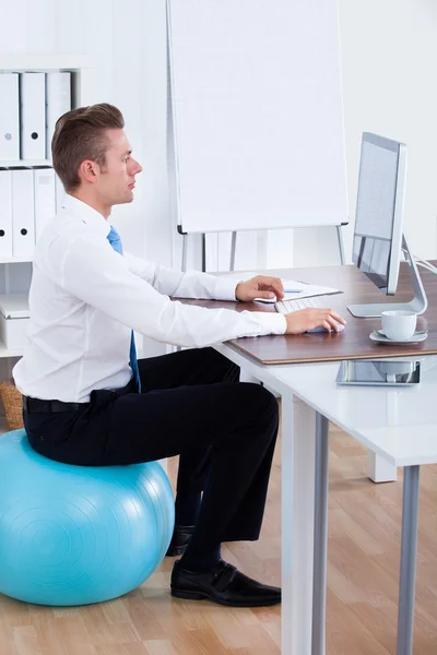 Zakenman zittend op een pilates bal en met behulp van computer — Stockfoto