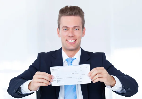 Бизнесмен, держащий чек — стоковое фото