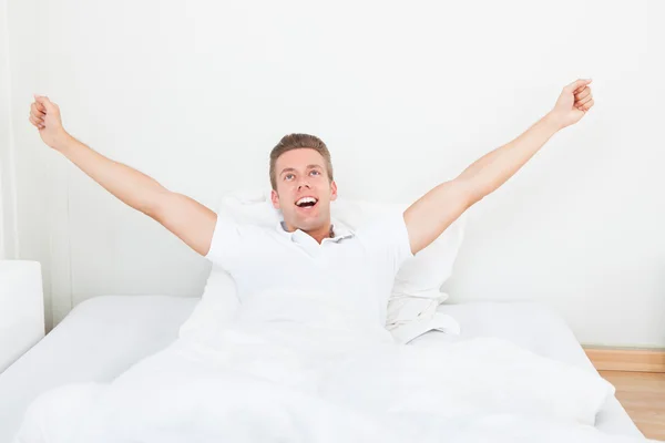 Homem acordando de manhã e se alongando na cama — Fotografia de Stock