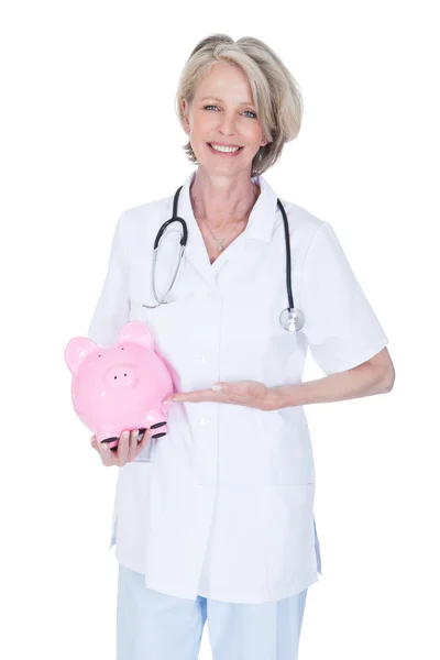 Érett nő orvos üzem Piggybank — Stock Fotó