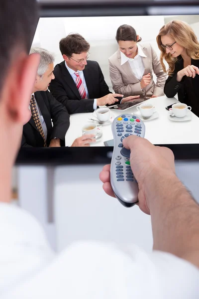 Hombre cambiando de canal de televisión a través de control remoto — Foto de Stock