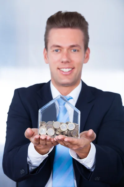 Бизнесмен вставляет монеты в коробку — стоковое фото