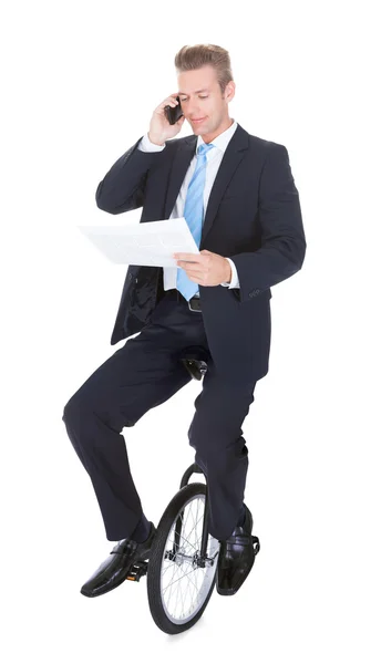 핸드폰에 얘기 하는 외 발 자전거에 앉아 사업 — 스톡 사진
