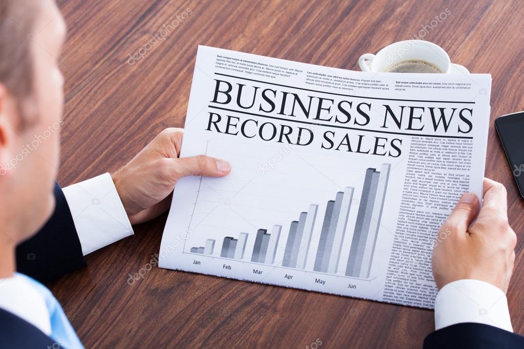 Close-up Of Young Businessman Reading News