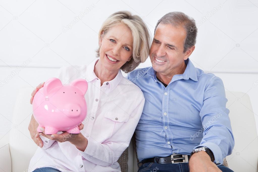 Mature Couple Calculating Coin In The Piggybank