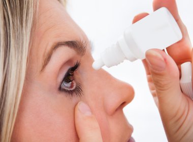 Woman pouring drops in her eyes clipart