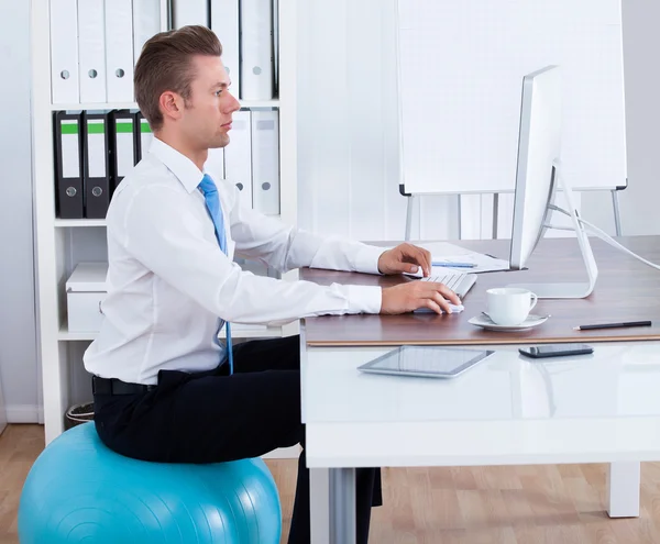 Empresário sentado em Pilates Ball e usando o computador — Fotografia de Stock