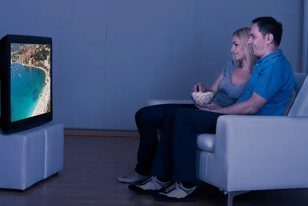 Pareja feliz comiendo palomitas de maíz y viendo televisión —  Fotos de Stock