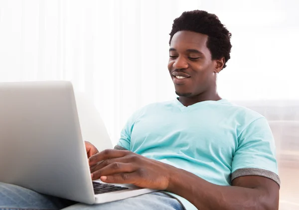 Feliz joven usando el ordenador portátil — Foto de Stock