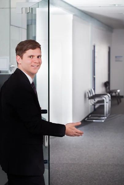 Jovem empresário dando boas-vindas à porta — Fotografia de Stock