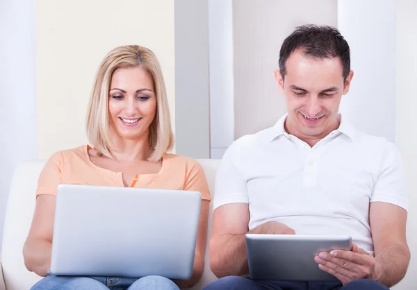 Casal adulto médio usando laptop e tablet digital — Fotografia de Stock