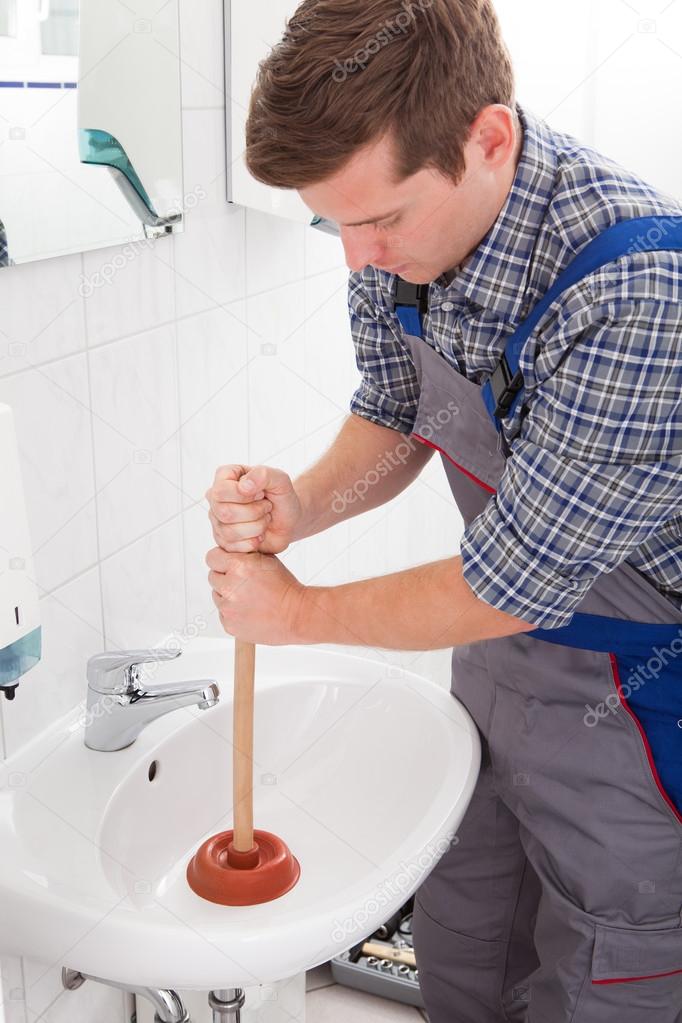Portrait of male plumber pressing plunger