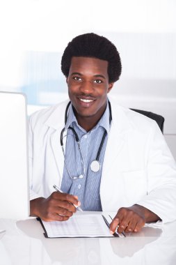 Masa başında oturan stetoskop ile mutlu doktor