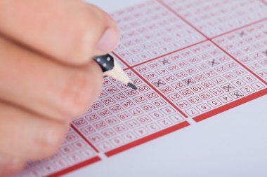 Person Marking Number On Lottery Ticket clipart