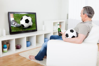 Olgun adam televizyonda futbol izlerken