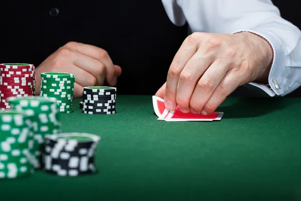 Mano humana del jugador de poker con cartas y fichas — Foto de Stock