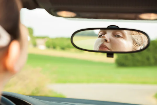 Mujer mirando espejo en coche — Foto de Stock