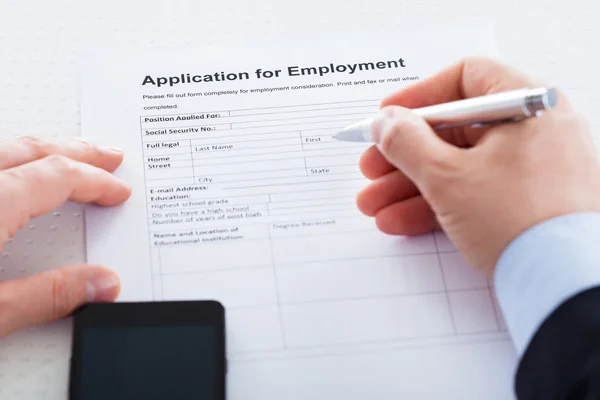 Close-up de mão segurando caneta sobre a aplicação de emprego — Fotografia de Stock