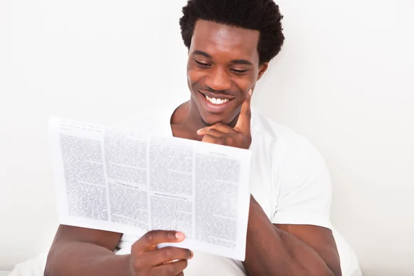 Młody człowiek Afryki czytanie gazety — Zdjęcie stockowe