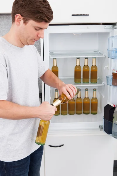 Young man standing beside the refrigerator — Stock Photo, Image