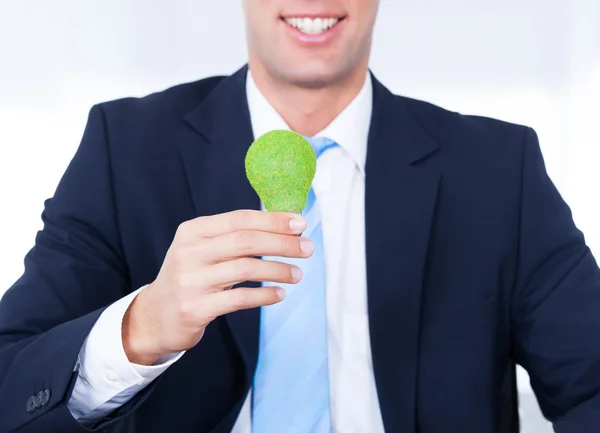 Biznesmen trzyma żarówkę z zielonej trawie — Zdjęcie stockowe