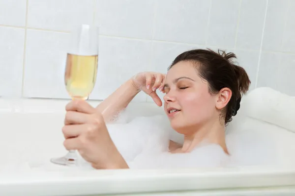 Женщина в ванной пьет шампанское — стоковое фото