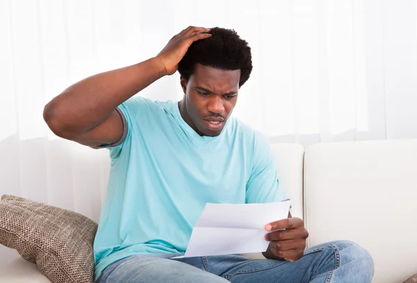 Hombre joven preocupado mirando el papel — Foto de Stock