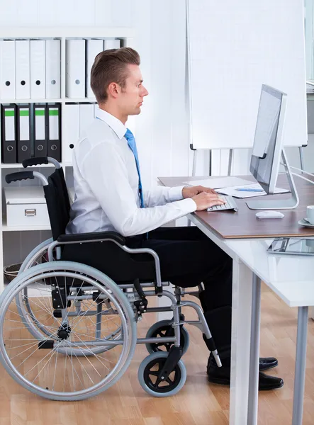 Empresario sentado en silla de ruedas y usando computadora — Foto de Stock