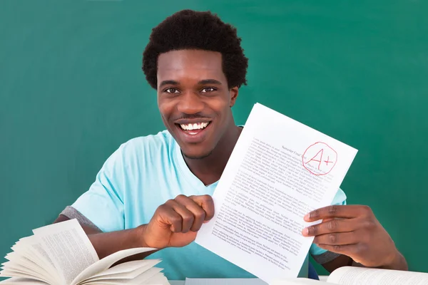 Молодой человек показывает документ с отличной оценкой плюс — стоковое фото