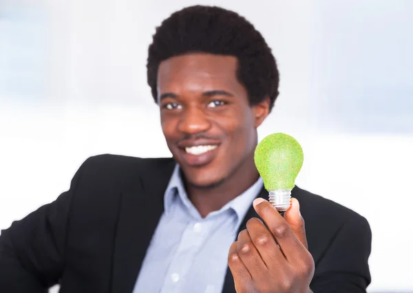 Бизнесмен держит лампочку с зеленой травой — стоковое фото