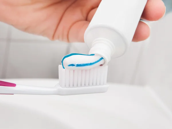 Mão segurando uma escova de dentes com pasta — Fotografia de Stock