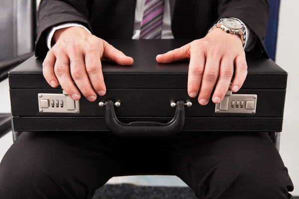 Businessman sitting and holding briefcase — Stock Photo, Image