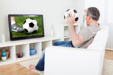 Olgun adam televizyonda futbol izlerken