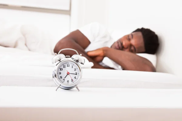 Een man is slapen met een wekker — Stockfoto