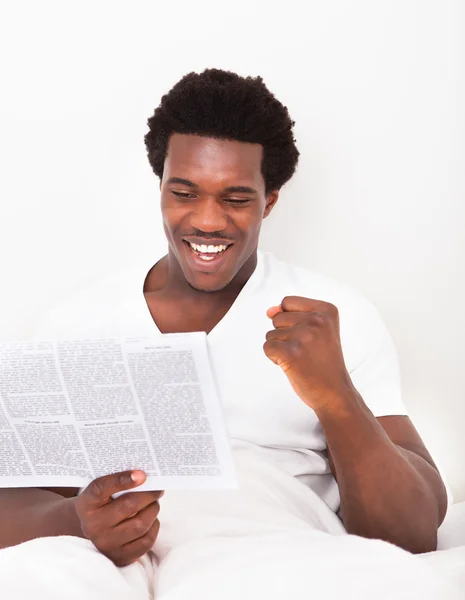 Jonge Afrikaanse man lezing krant — Stockfoto