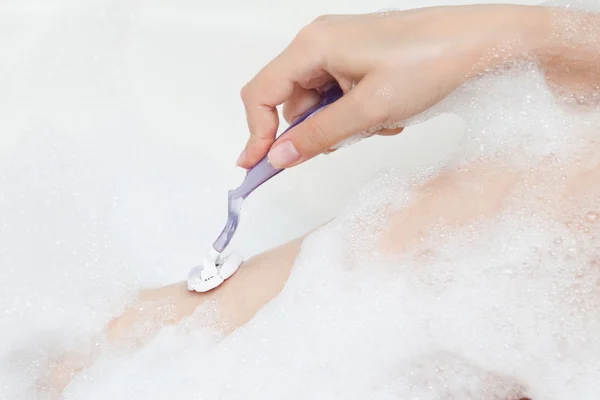 Женщина в ванной бреет ногу — стоковое фото