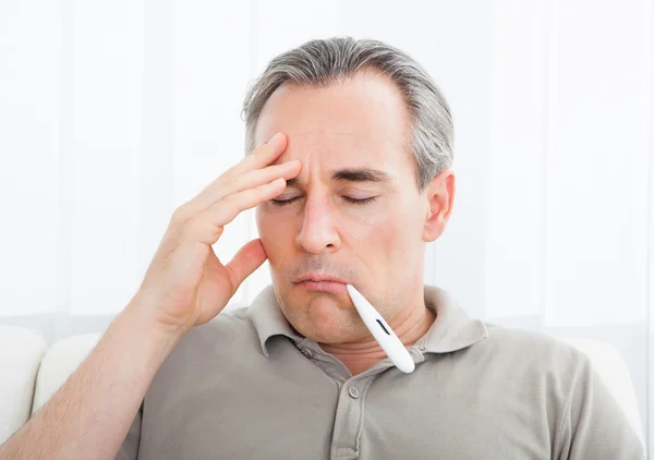 Зрелый больной человек с термометром во рту — стоковое фото