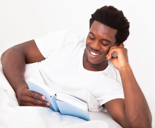 Genç adam yatakta kitap okuma — Stok fotoğraf