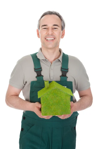Счастливчик держит дом, покрытый травой — стоковое фото