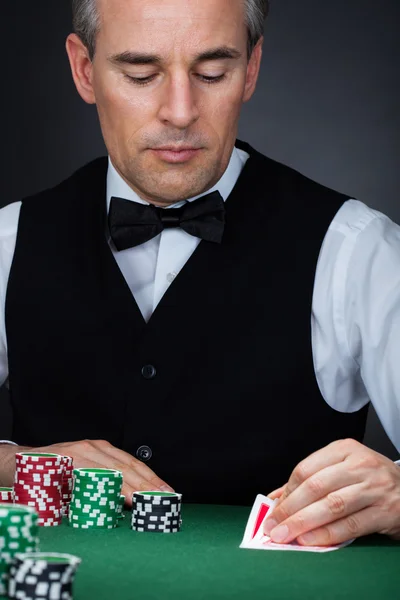 Menselijke hand van pokerspeler met kaarten en chips Stockfoto