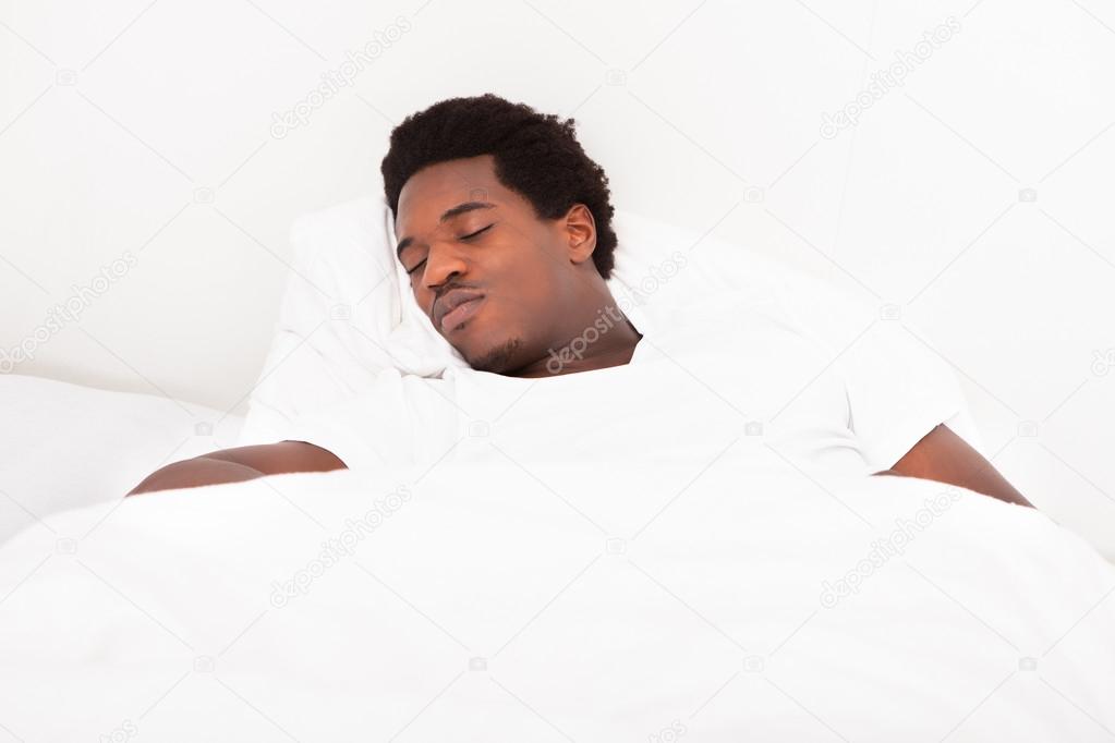 Young African Man Sleeping In Bed