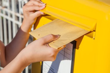 Woman inserting envelope in mailbox clipart