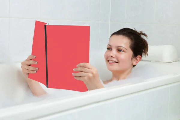 Wanita muda di buku bacaan bak mandi — Stok Foto