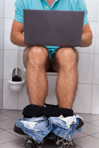 Людина в туалеті за допомогою ноутбука — стокове фото