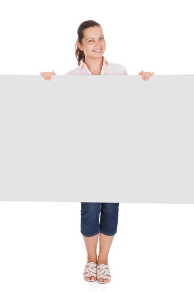 Giovane donna che punta sul cartello bianco — Foto Stock